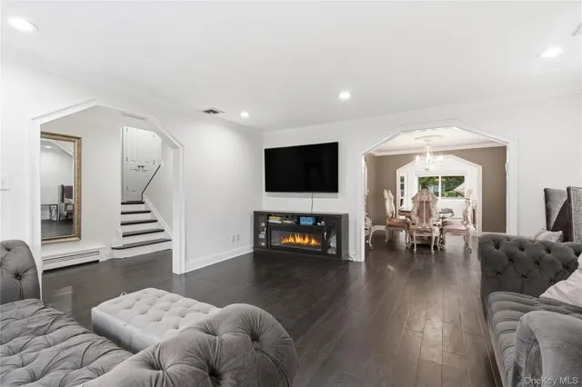 a living room with furniture and a flat screen tv with kitchen view