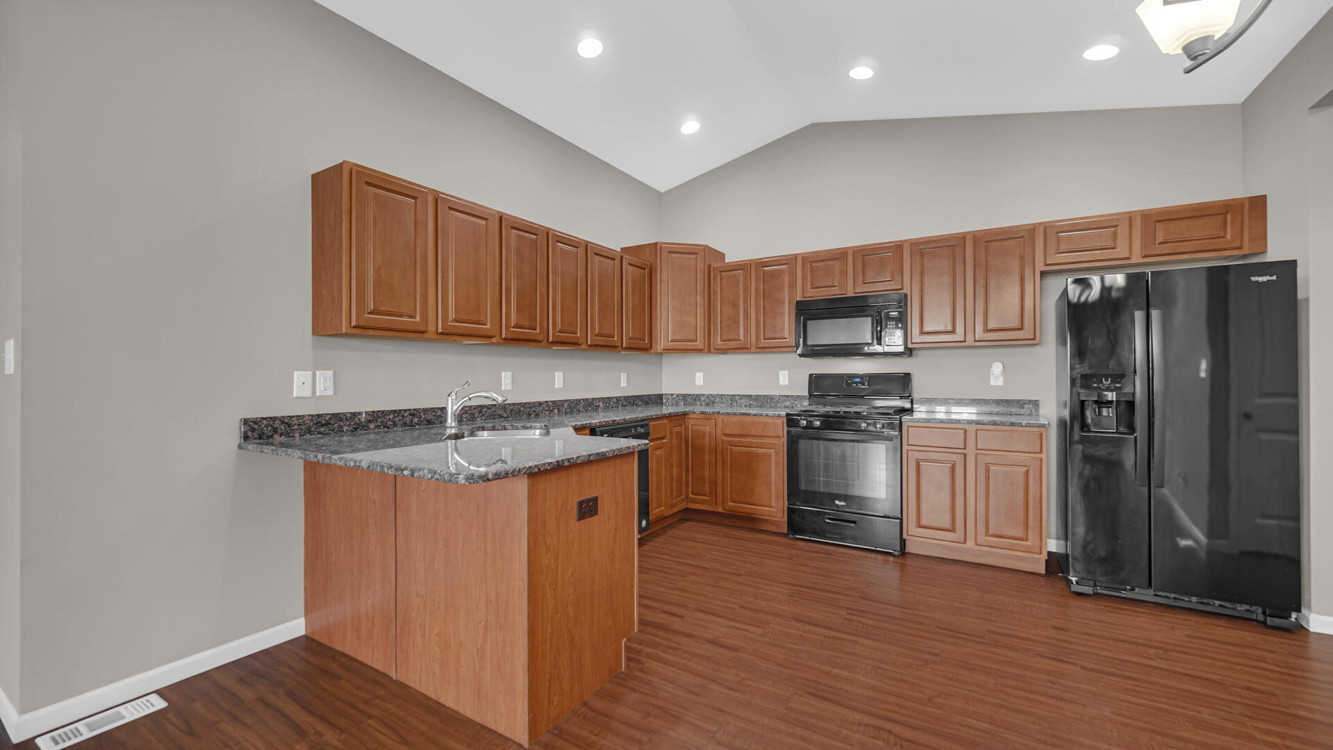 3889-91 Stadium Street Portage, IN 46368 - Photo 8 of 23 a kitchen with stainless steel appliances granite countertop a stove a sink dishwasher a refrigerator and a microwave oven with wooden floor