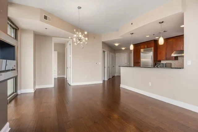 a view of a hallway with wooden floor and a kitchen