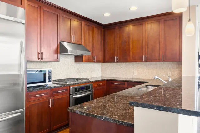 a kitchen with granite countertop a sink stove and cabinets
