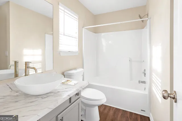 a bathroom with a granite countertop sink toilet a mirror and shower