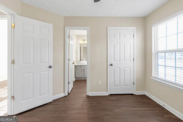 an empty room with wooden floor windows and front door