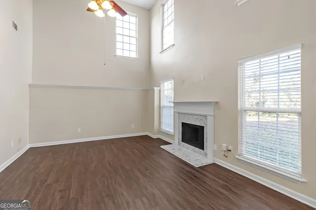 an empty room with wooden floor windows and fireplace