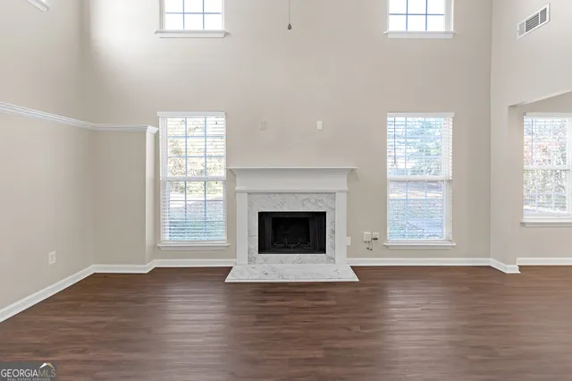 an empty room with wooden floor windows and fireplace