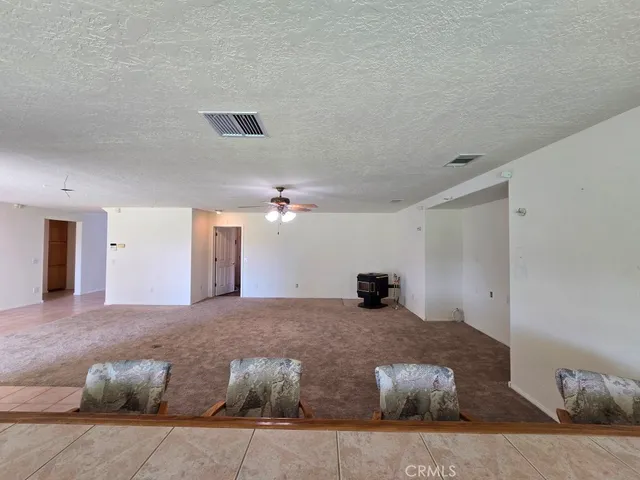 a view of an empty room with chandelier fan and fire place