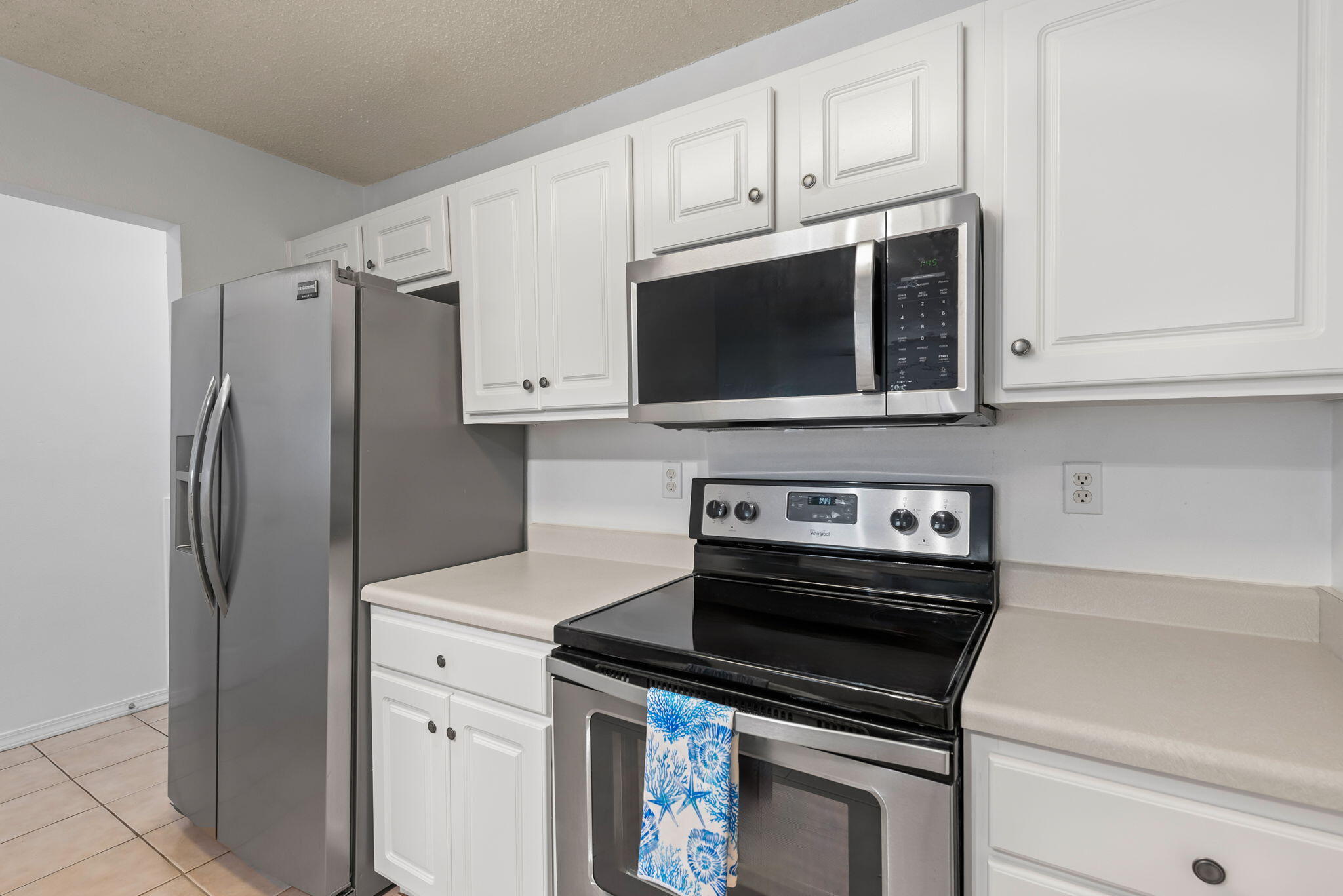 498 Keystone Road Mary Esther, FL 32569 - Photo 8 of 21 a kitchen with stainless steel appliances white cabinets white stove a microwave and a refrigerator