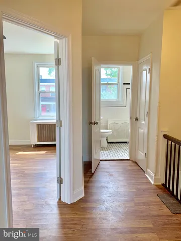 a view of a hallway view with wooden floor and a living room