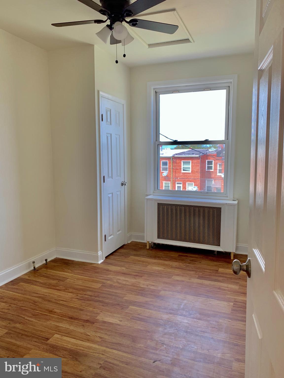 3542 Lyndale Avenue Baltimore, MD 21213 - Photo 8 of 12 a view of an empty room with a window and wooden floor