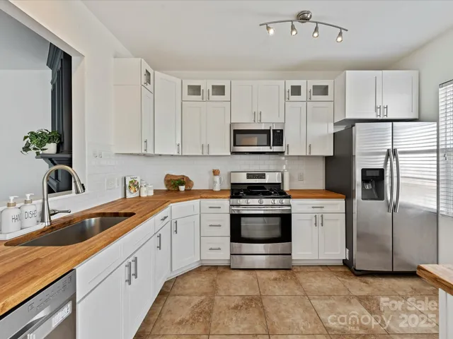 a kitchen with stainless steel appliances granite countertop a sink a stove a refrigerator and cabinets