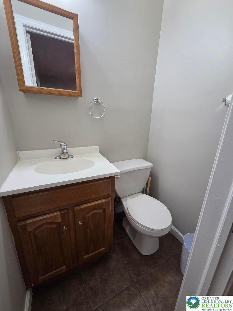 1747 Schoenersville Road Bethlehem, PA 18018 - Photo 8 of 13 A compact and functional powder room with a vanity sink, toilet, and simple mirror.