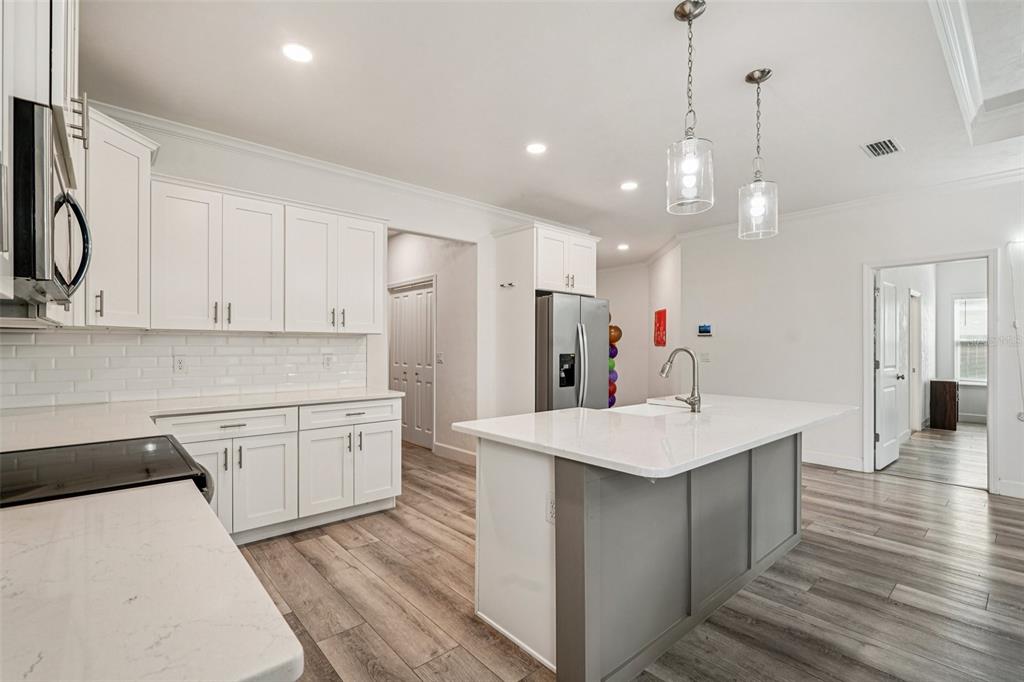6657 Southwest 15 Place Gainesville, FL 32607 - Photo 7 of 23 a kitchen with stainless steel appliances kitchen island granite countertop a sink a stove a refrigerator and white cabinets with wooden floor