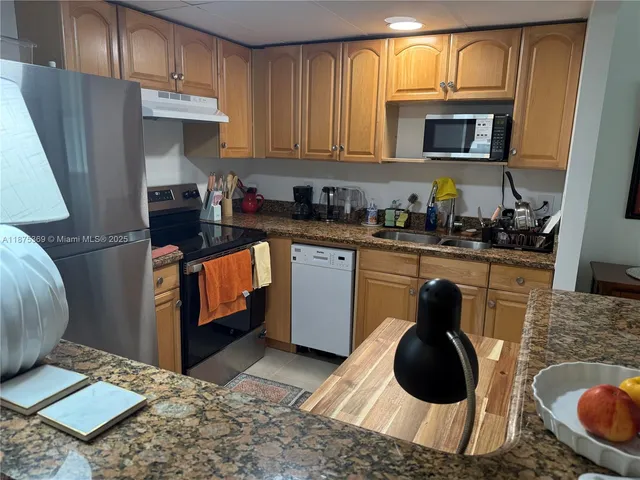a kitchen with stainless steel appliances granite countertop a sink stove refrigerator and cabinets