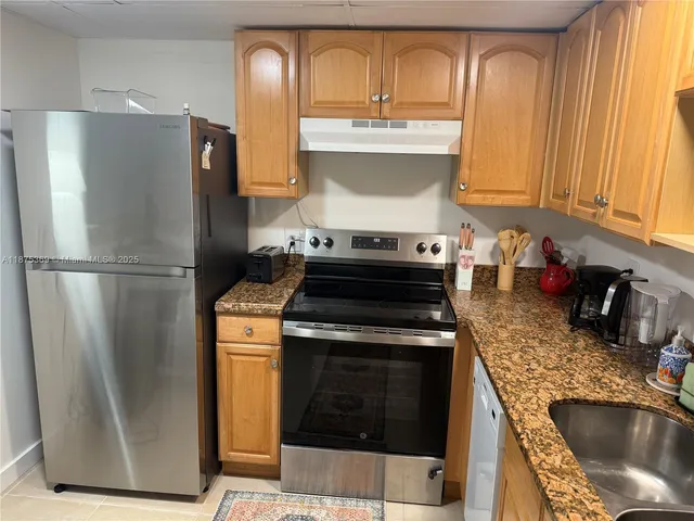 a kitchen with granite countertop a refrigerator stove and sink