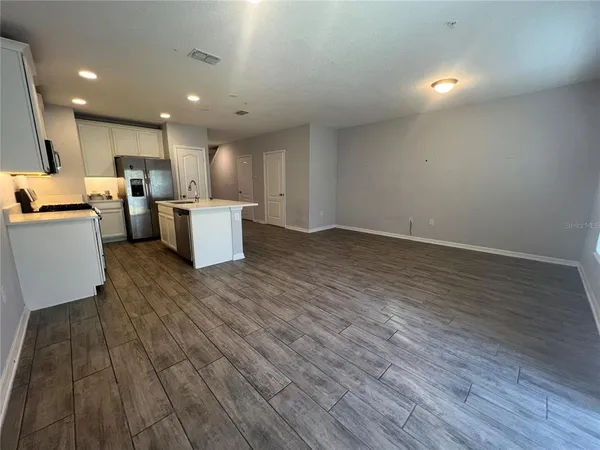 a view of kitchen with kitchen island wooden floors appliances and furniture