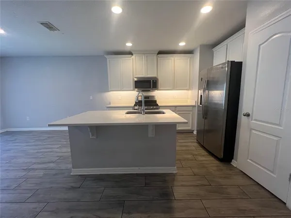a kitchen with stainless steel appliances granite countertop a refrigerator a stove and a sink