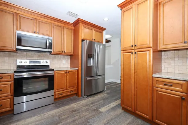 an empty room with wooden floor ceiling fan and windows