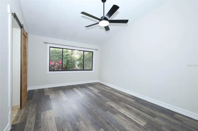 an empty room with wooden floor ceiling fan and windows