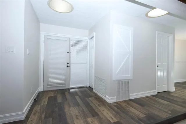 an empty room with wooden floor and entrance