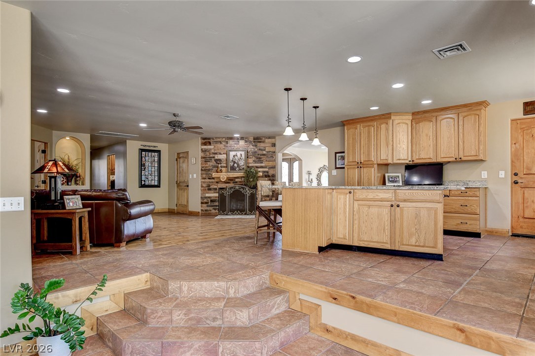 1950 Bowman Road Logandale, NV 89021 - Photo 18 of 81 An inviting open-concept living space features a stone fireplace and a functional kitchen island, uniting comfort with culinary convenience.