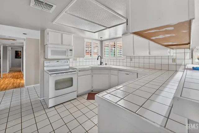 a kitchen with a sink a stove cabinets and utility room