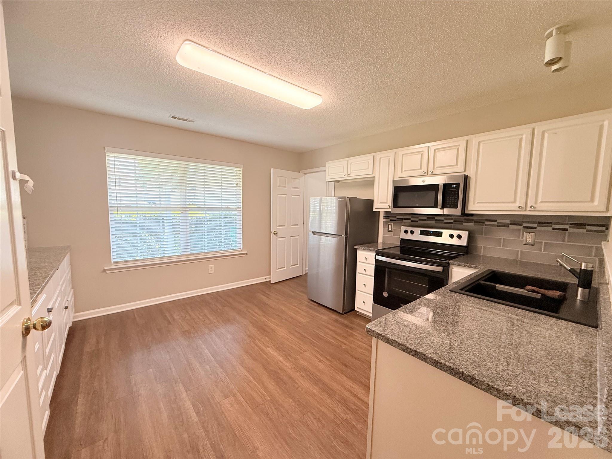10553 Gold Pan Road Charlotte, NC 28215 - Photo 5 of 15 a kitchen with wooden floors and stainless steel appliances
