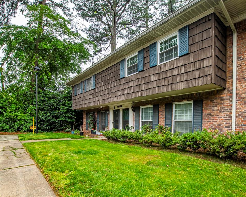 a view of a house with a yard plants and large tree