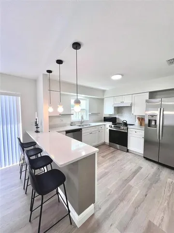 a kitchen with stainless steel appliances kitchen island granite countertop a sink a stove and chairs