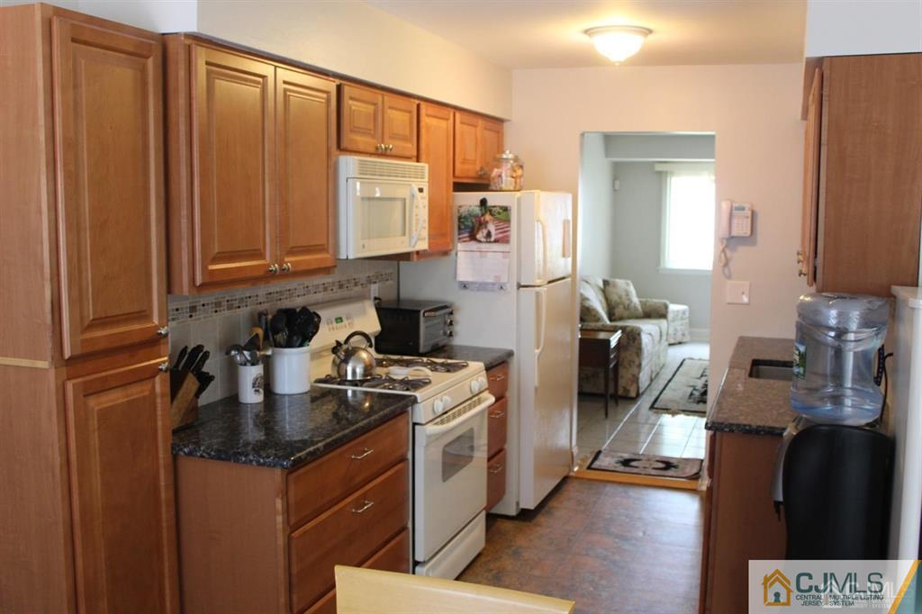 2 R Quincy Circle, Unit R2 Dayton, NJ 08810 - Photo 1 of 18 a kitchen with stainless steel appliances granite countertop a refrigerator a stove and a sink with wooden floor