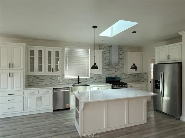 a kitchen with stainless steel appliances a sink stove refrigerator and cabinets