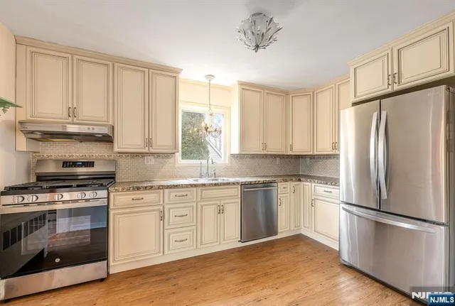 a kitchen with granite countertop white cabinets and stainless steel appliances
