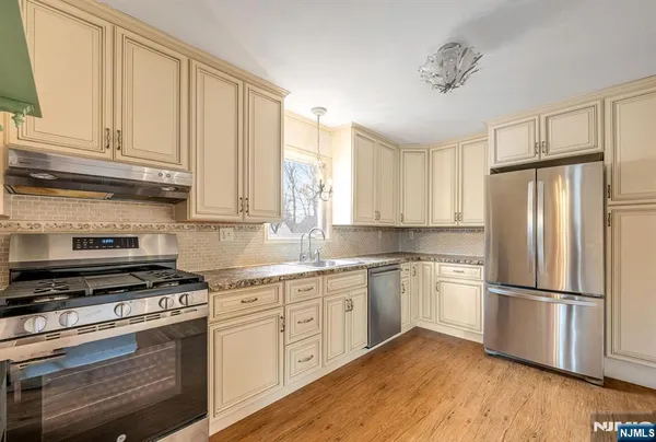 a kitchen with cabinets stainless steel appliances a sink and a window