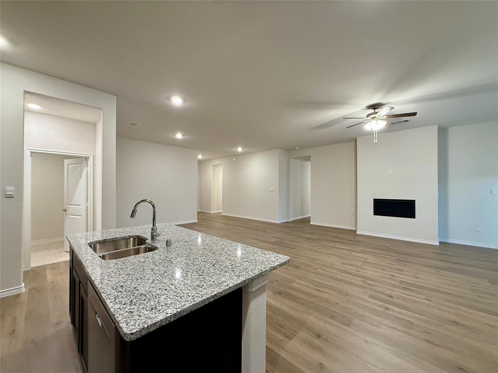 2025 Eugene Street Anna, TX 75409 - Photo 8 of 32 a kitchen island with granite countertop a sink cabinets and wooden floor