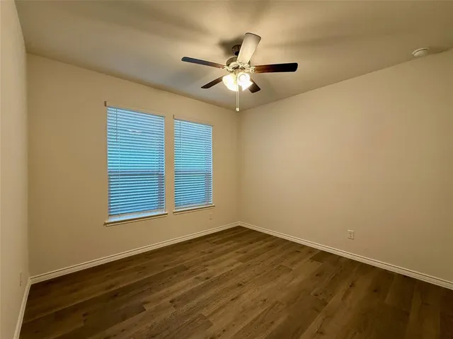 an empty room with chandelier fan and windows