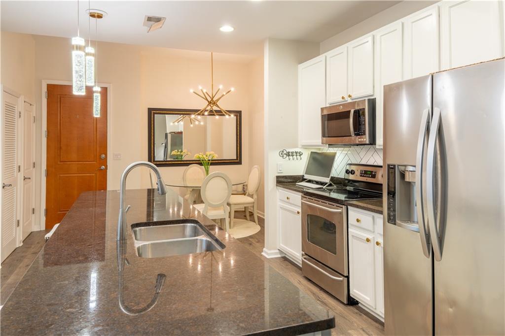 3040 Peachtree Road Northwest, Unit 1602 Atlanta, GA 30305 - Photo 3 of 12 a kitchen with stainless steel appliances granite countertop a refrigerator a stove and a sink with wooden floor