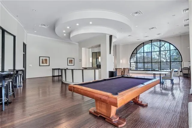 a living room with table a pool table and a large window