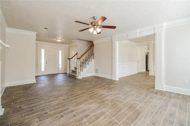a view of a livingroom with wooden floor a ceiling fan and staircase
