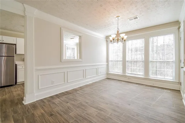 a view of an empty room with a window and wooden floor