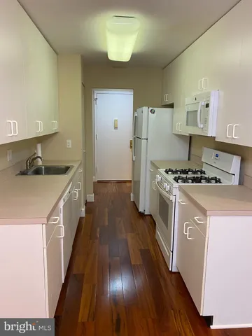 a kitchen with sink a refrigerator and wooden floor