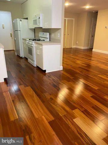 a kitchen with stainless steel appliances wooden floor and a refrigerator