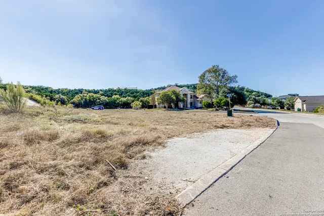 a view of a dry yard with a wooden fence