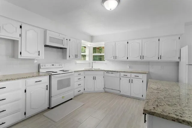 a kitchen with granite countertop white cabinets white stainless steel appliances with a sink and dishwasher