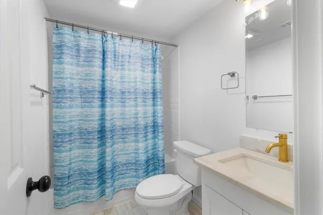 a bathroom with a sink a toilet and shower curtain