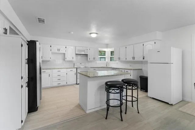 a kitchen with stainless steel appliances a refrigerator a stove a sink and white cabinets with wooden floor