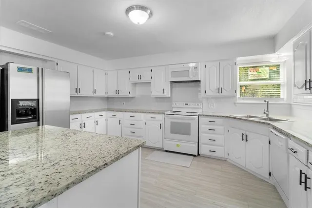 a kitchen with granite countertop a sink stainless steel appliances and cabinets
