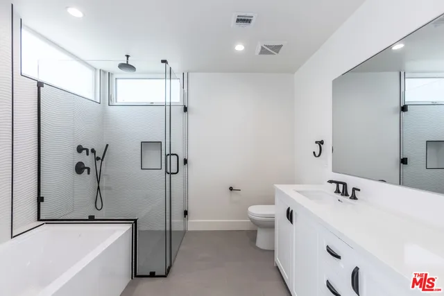 a bathroom with a bathtub shower sink mirror and toilet