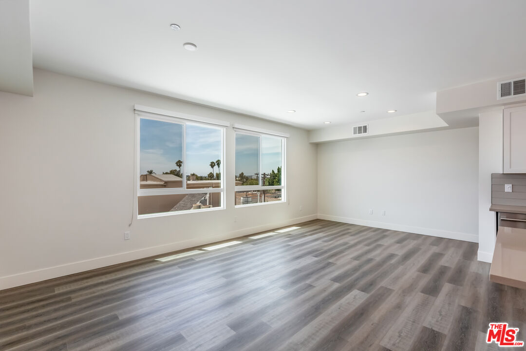 857 North Hayworth Avenue, Unit 403 Los Angeles, CA 90046 - Photo 24 of 52 a view of an empty room with wooden floor and a window