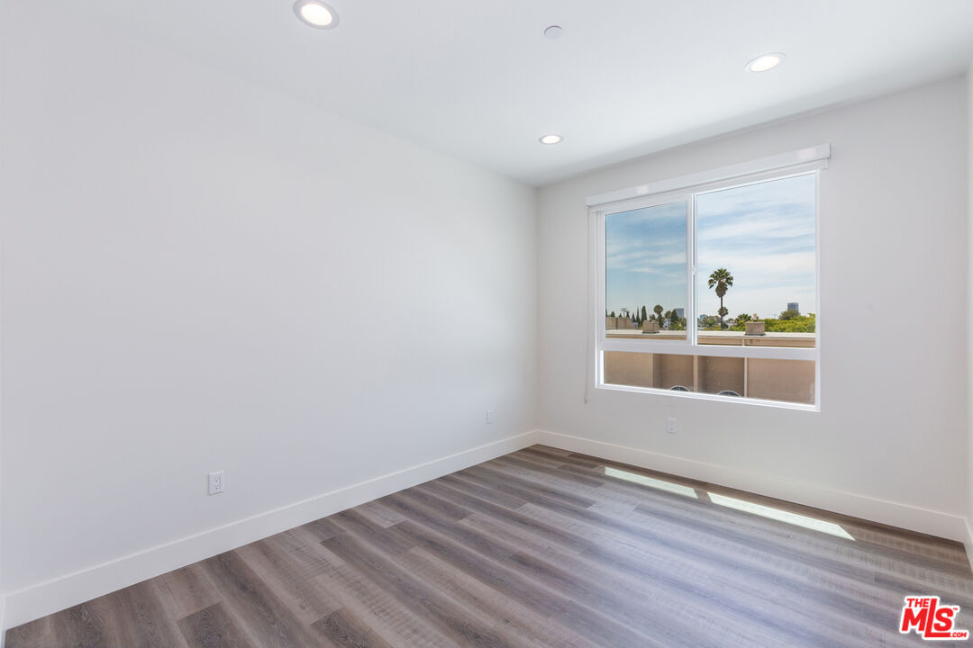 857 North Hayworth Avenue, Unit 403 Los Angeles, CA 90046 - Photo 29 of 52 an empty room with wooden floor and a window