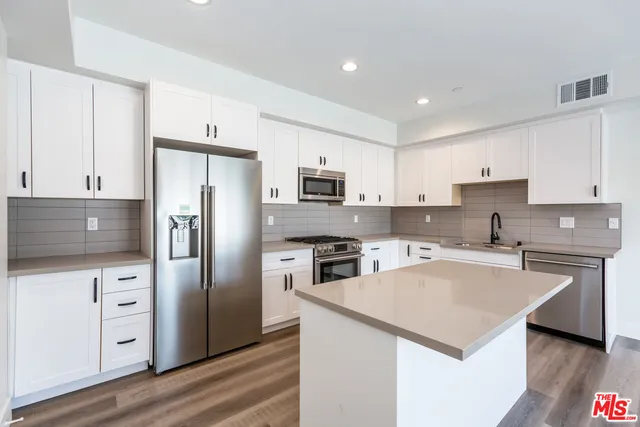 a kitchen with a refrigerator a stove top oven a sink and dishwasher with wooden floor