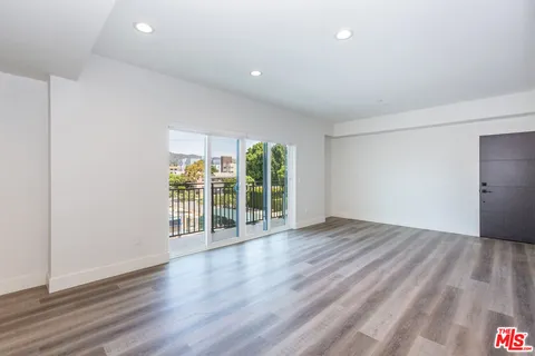 a kitchen with stainless steel appliances granite countertop a stove a sink and white cabinets with wooden floor