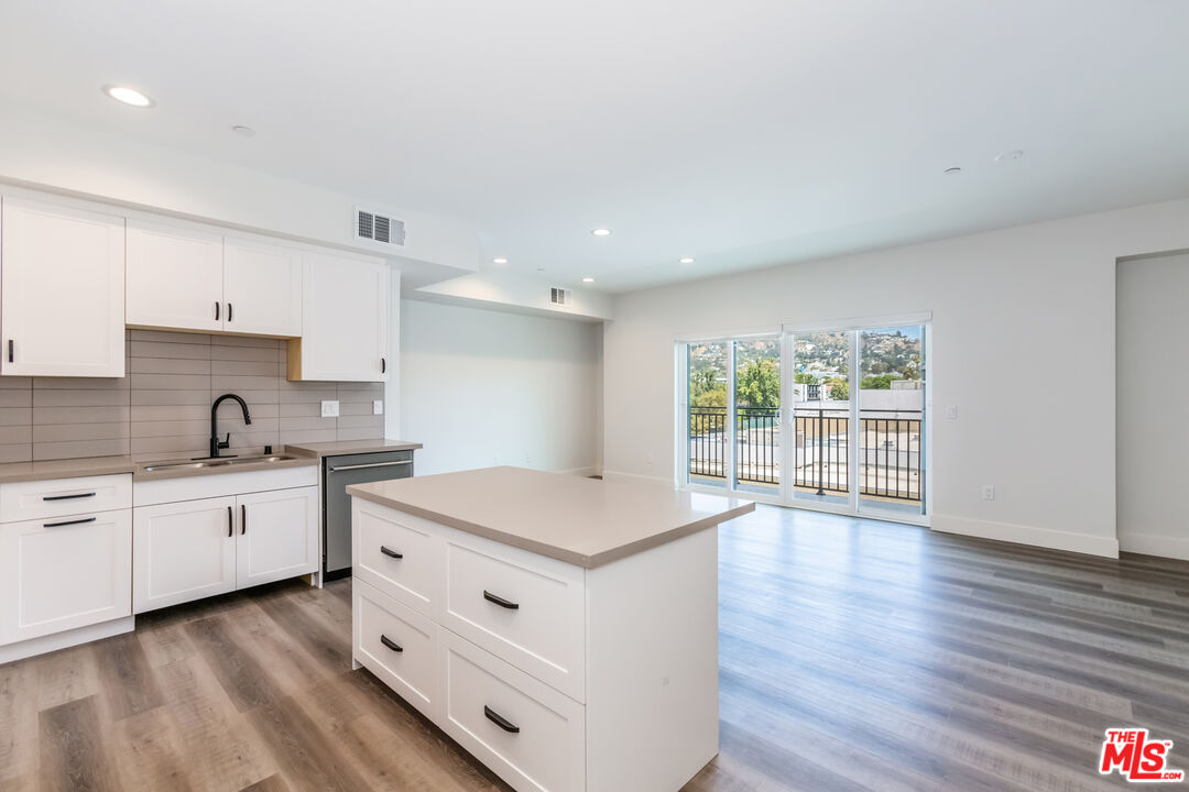 857 North Hayworth Avenue, Unit 403 Los Angeles, CA 90046 - Photo 34 of 52 a kitchen with stainless steel appliances granite countertop a stove a sink and white cabinets with wooden floor